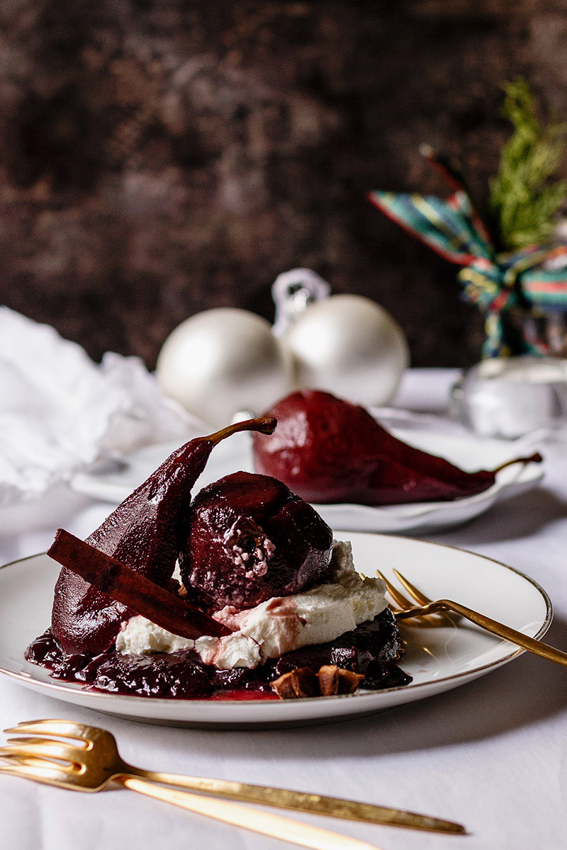 Peras con gelatina de vino y mascarpone en plato blanco con decoracion navideña
